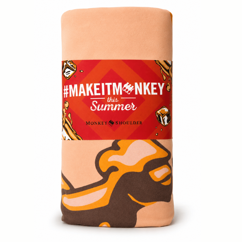 beach towel with a red label featuring '#MAKEITMONKEY this Summer' text on a white background.