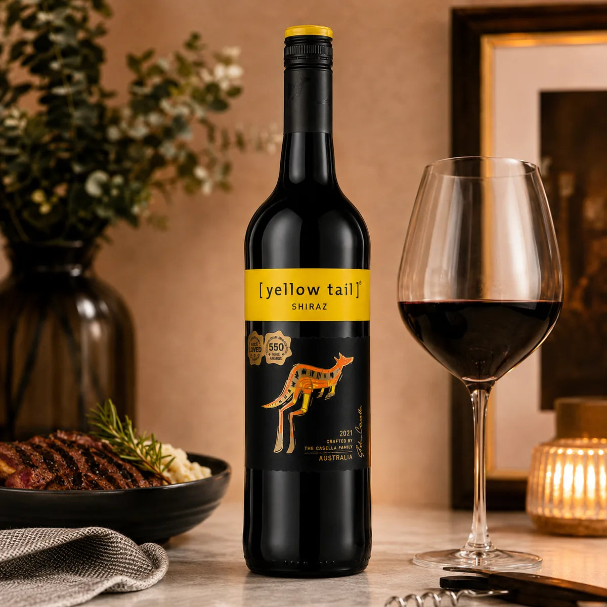 Yellow Tail Shiraz 750ml served in a red wine glass beside grilled steak and rosemary