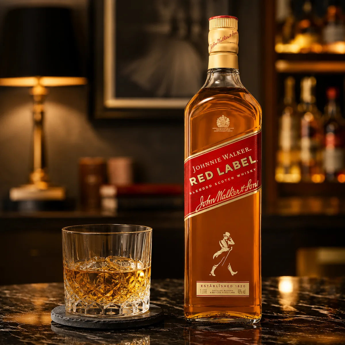 A bottle of Johnnie Walker Red Label whisky stands on a dark marble bar counter next to a cut glass filled with the amber liquid. The background shows a warmly lit bar interior with shelves and a lamp.