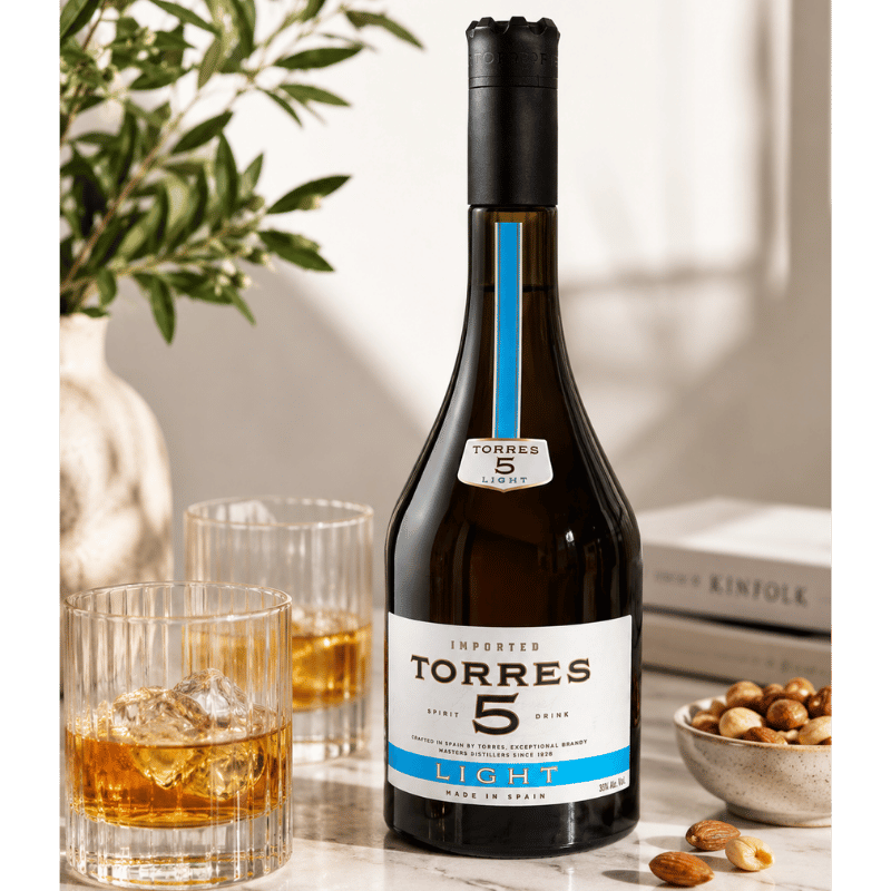 Torres 5 Light Spanish brandy served with whisky glasses and nuts on marble table